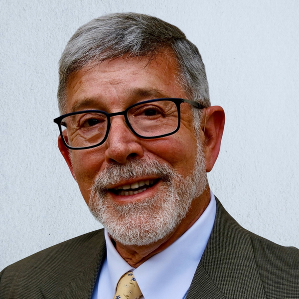 Jeff Leiter headshot, male in his early sixties with a white beard and mustache and hair, wearing black-rimmed glasses and a wool suit with a yellow tie