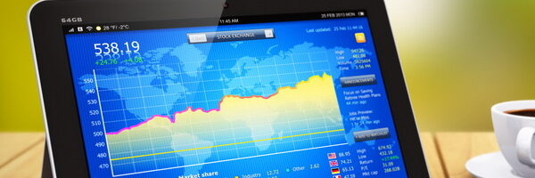 Tablet displaying bar graph placed next to cup of coffee, ballpoint pen and smartphone